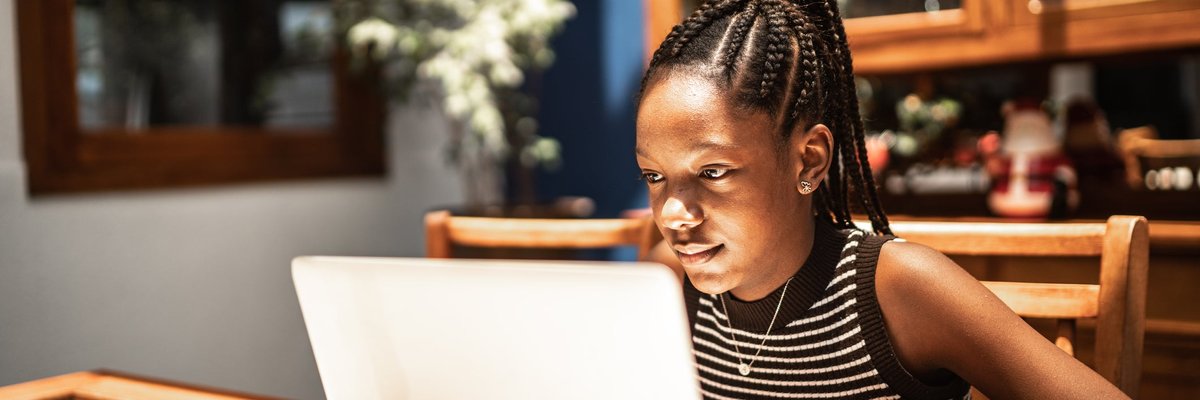 A teenager uses a laptop at home.