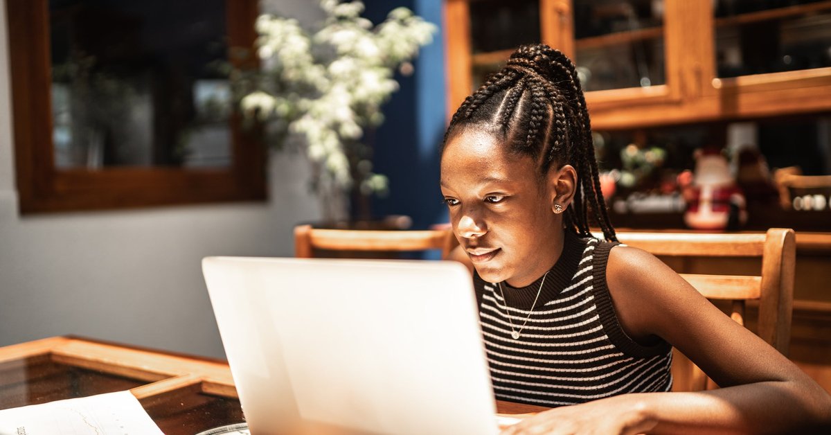 A teenager uses a laptop at home.