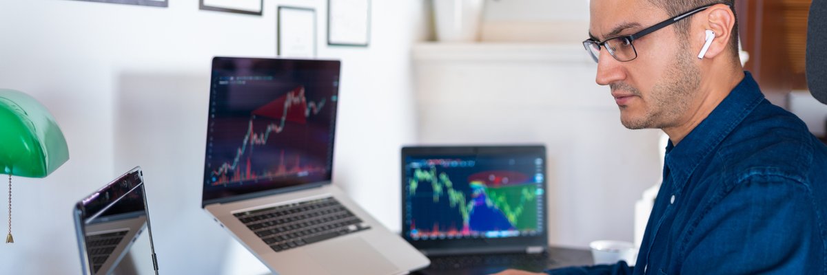 An investor analyzes the stock market with computer charts in their home office.