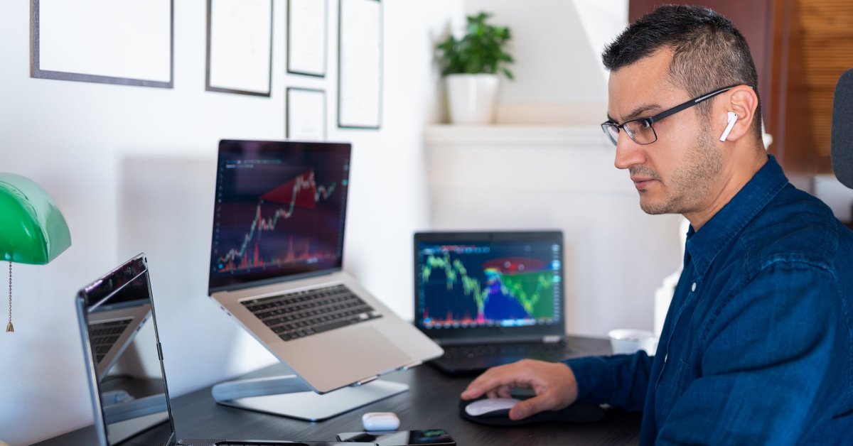 An investor analyzes the stock market with computer charts in their home office.