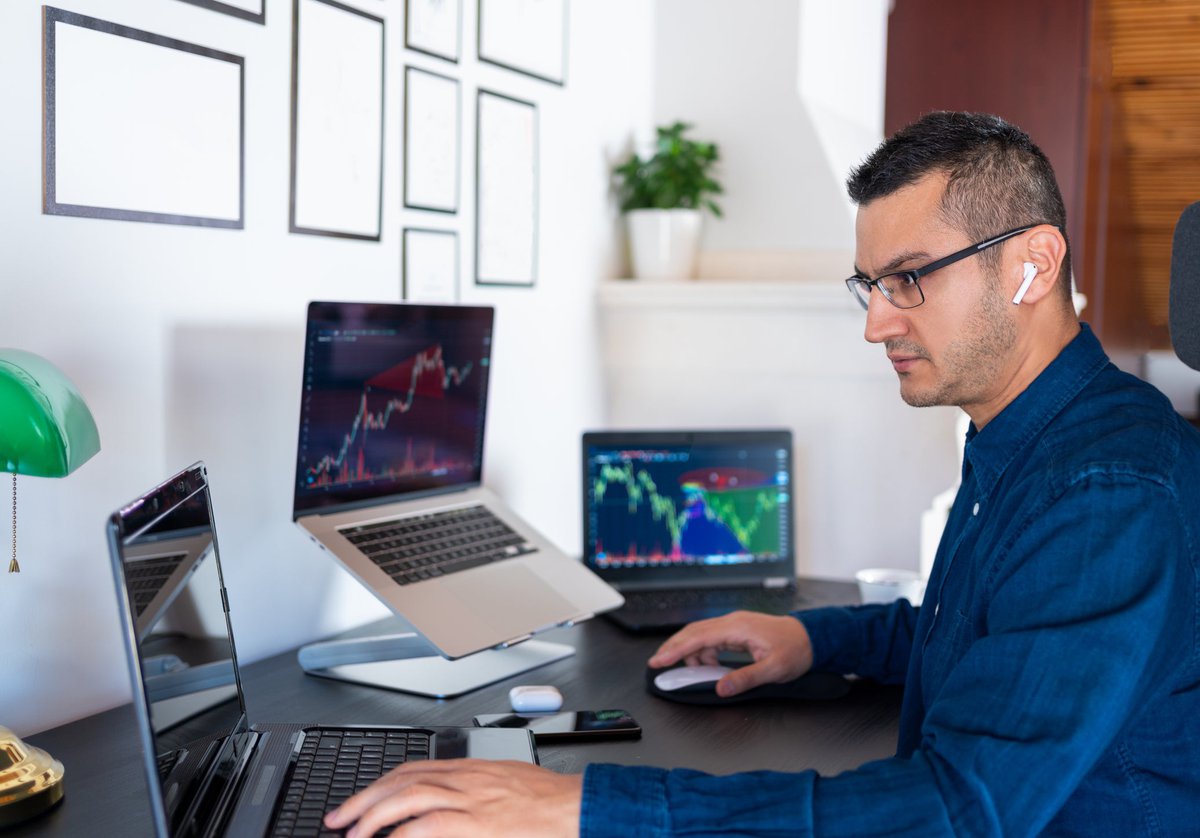 An investor analyzes the stock market with computer charts in their home office.