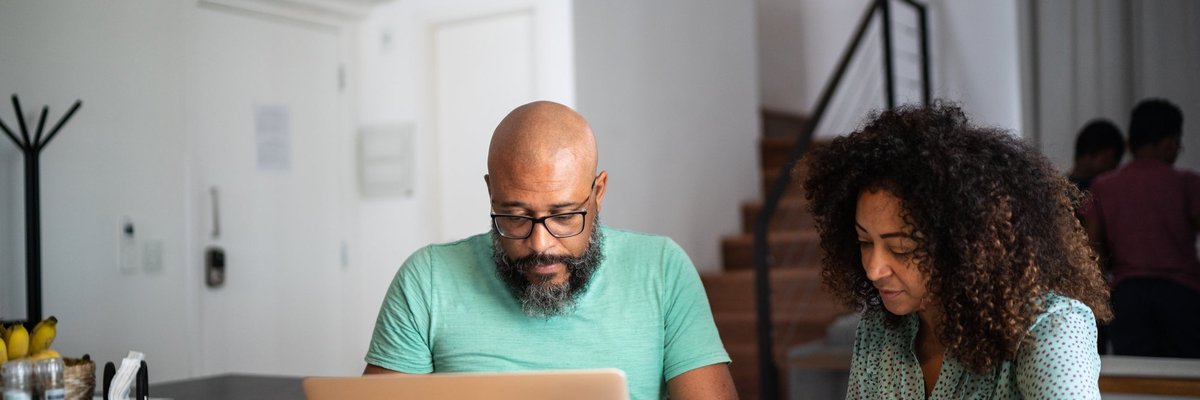 A couple does their personal finances using a laptop and notebook.