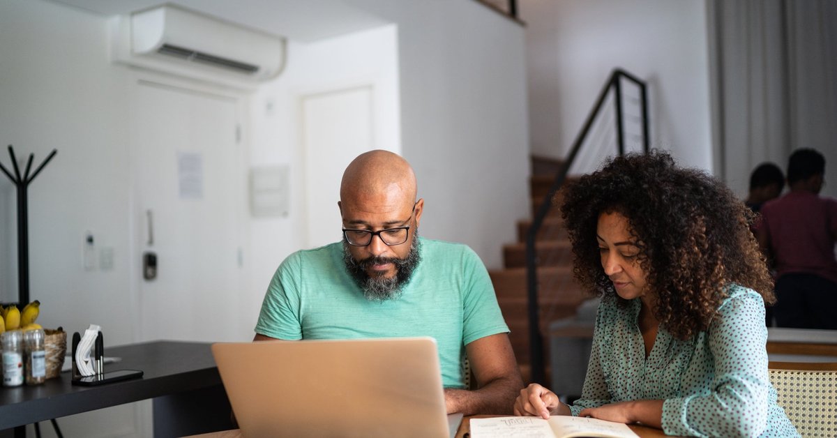 A couple does their personal finances using a laptop and notebook.