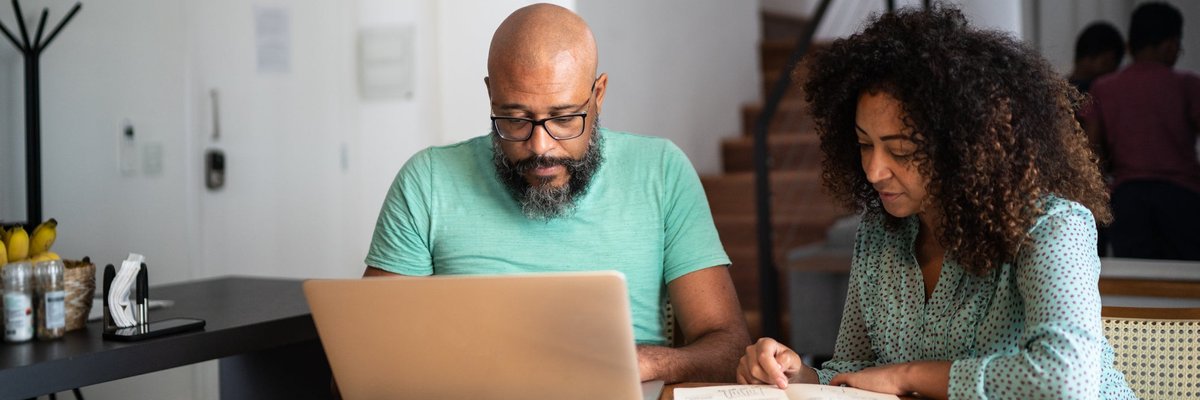 A couple does their personal finances using a laptop and notebook.