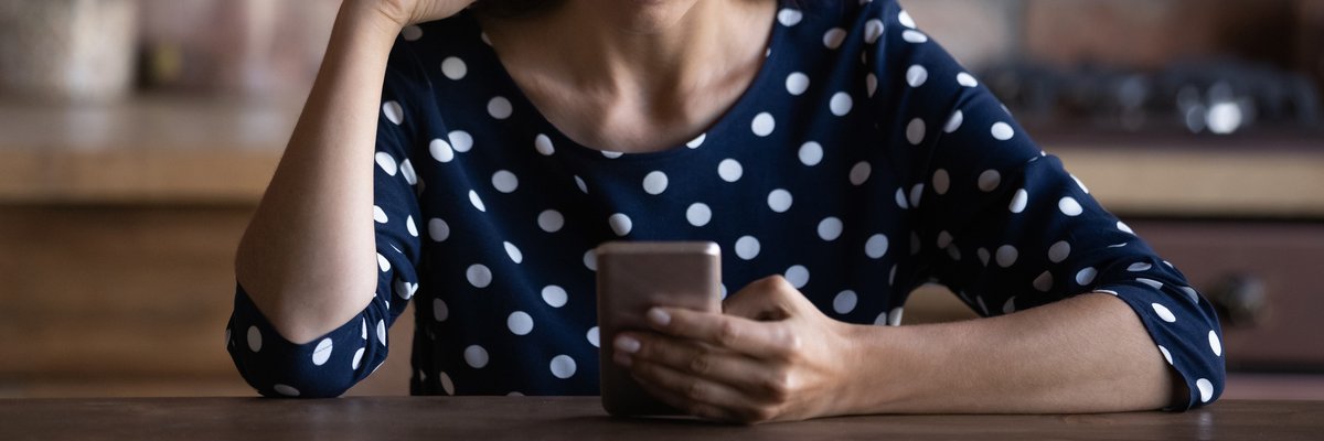An upset person with a creased brow looks at their smartphone screen.