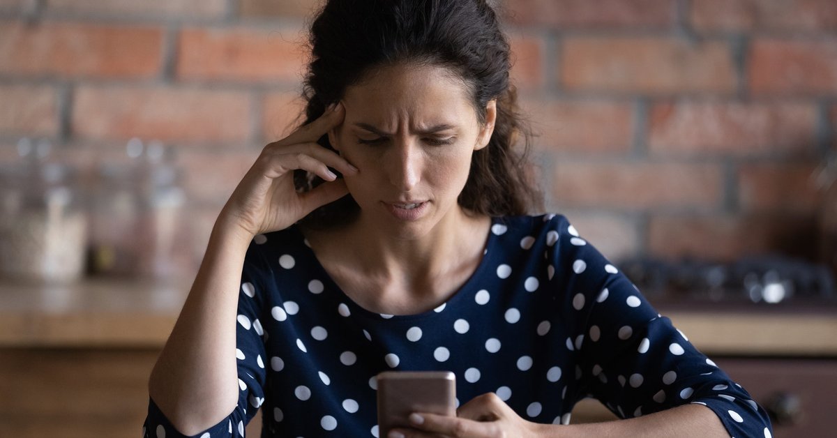 A smartphone user looks at the screen displeased.