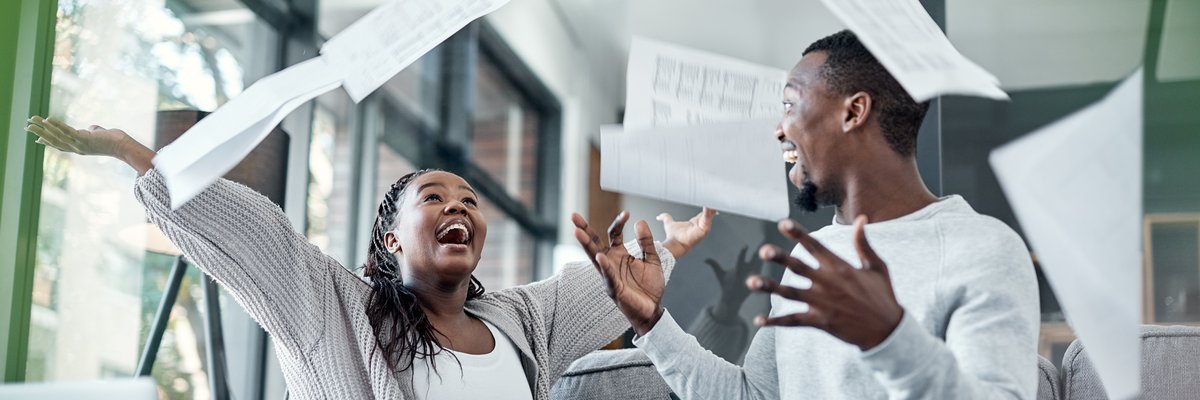Elated couple throwing papers in the air in celebration.