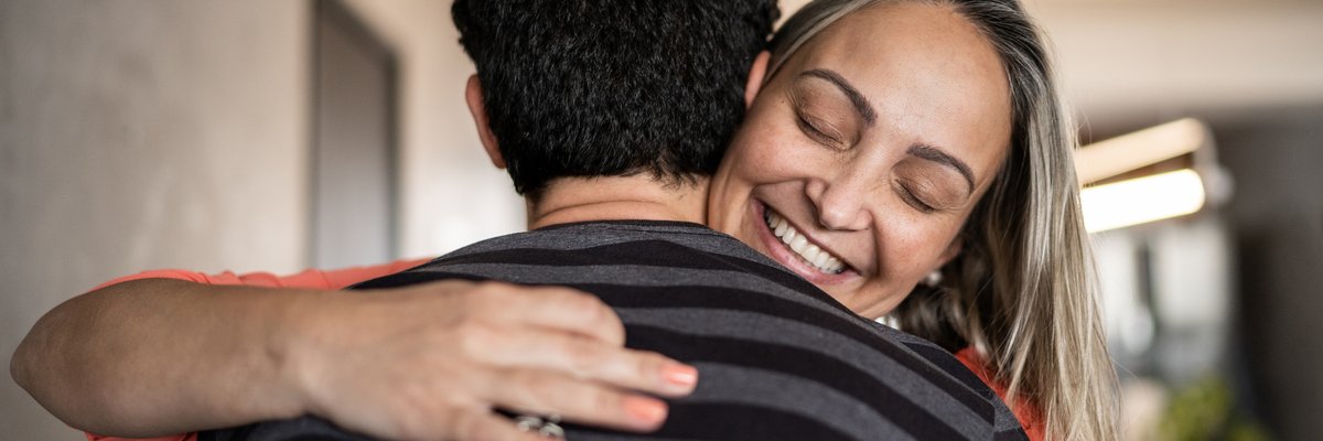 A couple embraces happily while one person holds a house key.