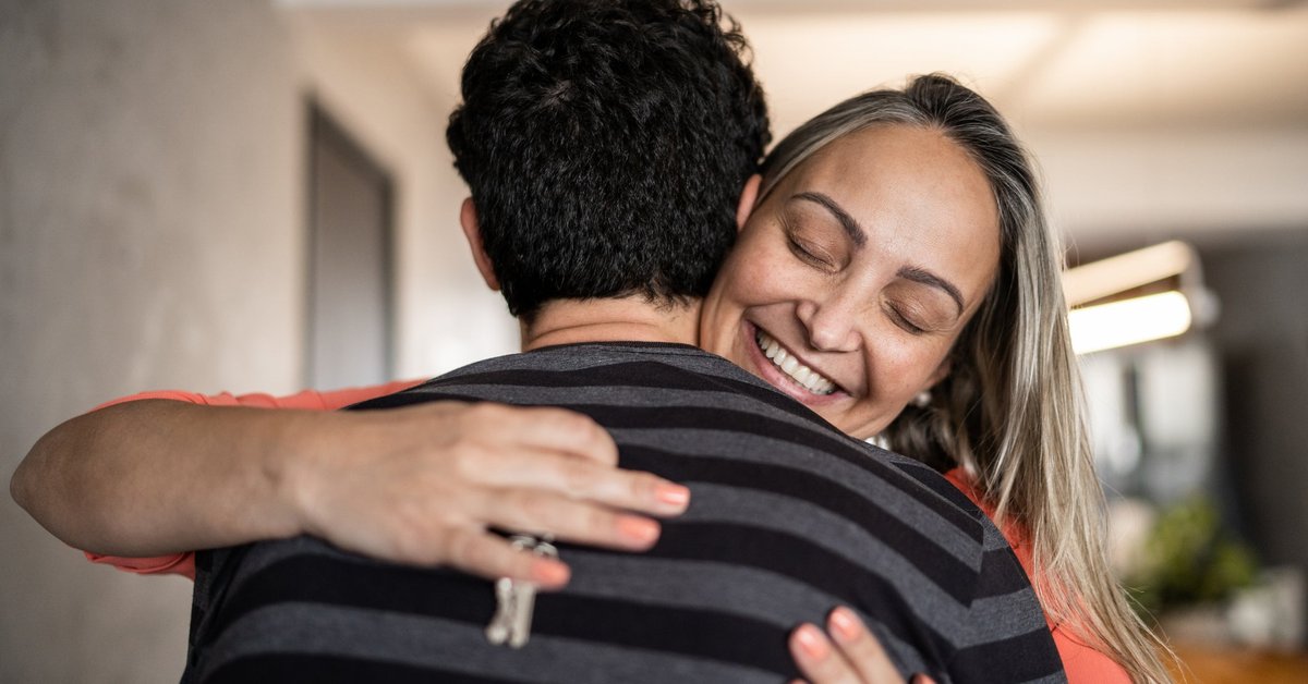 A couple embraces happily while one person holds a house key.