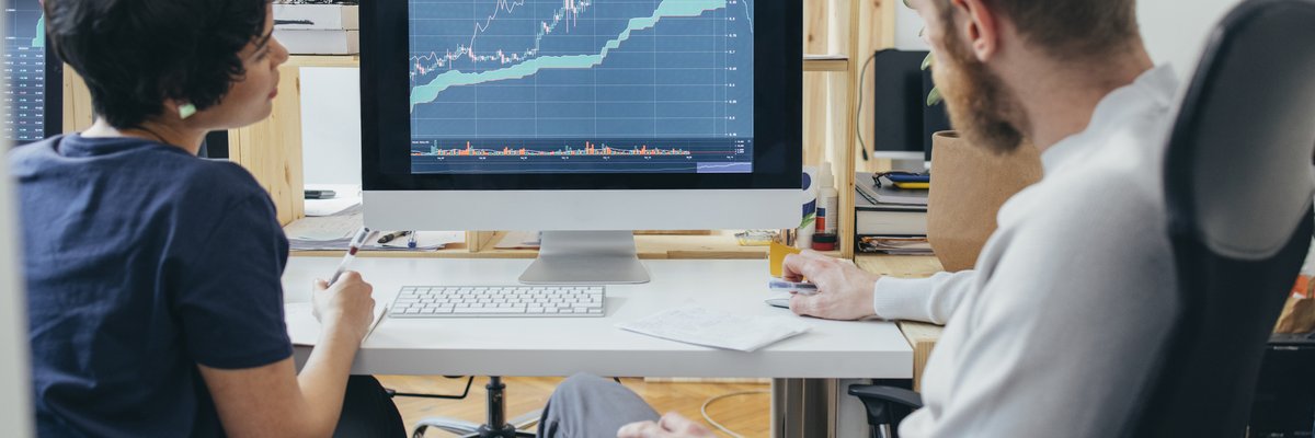 Two colleagues analyze a financial chart on a computer.