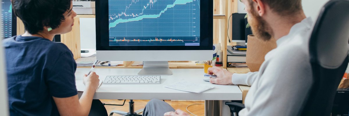 Two colleagues analyze a financial chart on a computer.