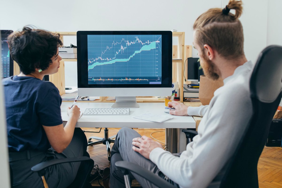 Two colleagues analyze a financial chart on a computer.