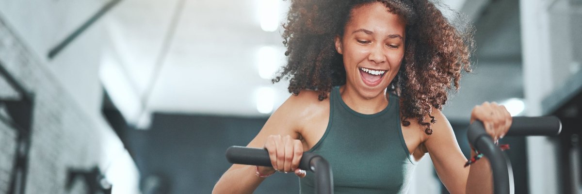 A woman happily works out on an indoor exercise bike.