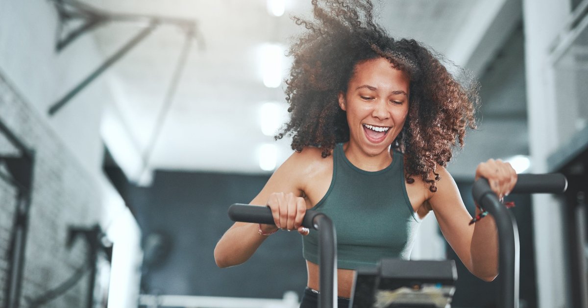 A woman happily works out on an indoor exercise bike.