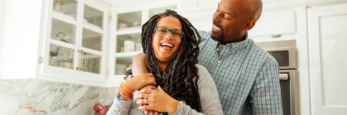 A middle-aged couple embraces happily in a kitchen.
