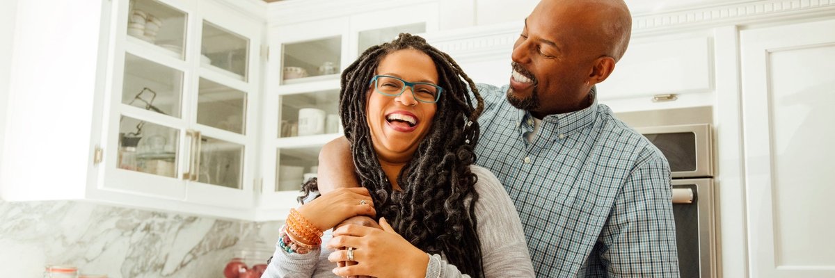 A middle-aged couple embraces happily in a kitchen.