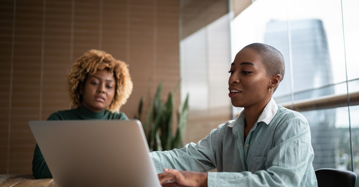 A business advisor uses a laptop while meeting with a client in their home.