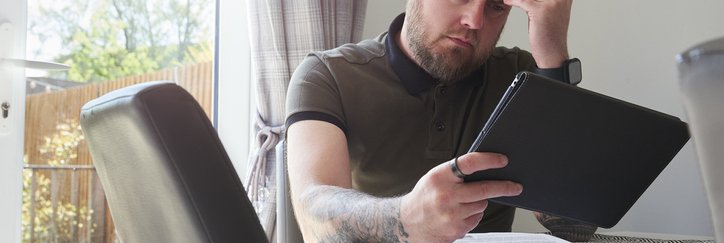 A homeowner looks worried as he reads through his household bills at the dining table.
