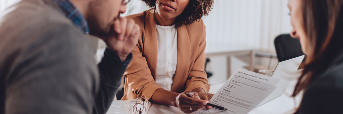 A couple decides whether to sign a loan agreement or not while sitting at a desk in a bank.