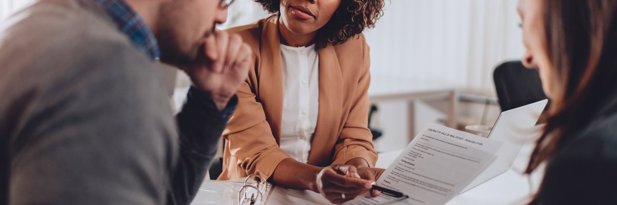 A couple decides whether to sign a loan agreement or not while sitting at a desk in a bank.