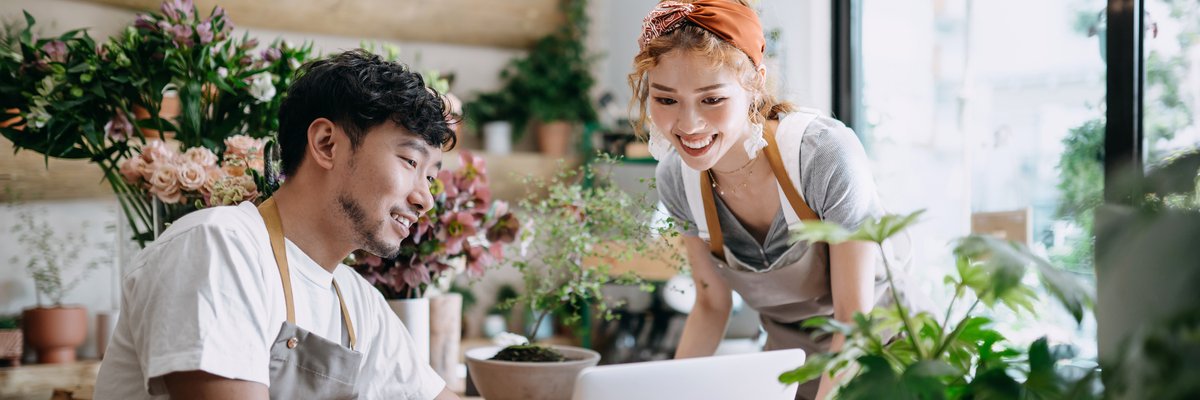 Small business owners looking at laptop in plant shop.