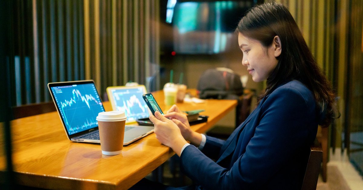 A business worker looks at crypto or stock graphs on their laptop.