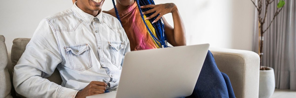 A couple uses a laptop on the couch at home.
