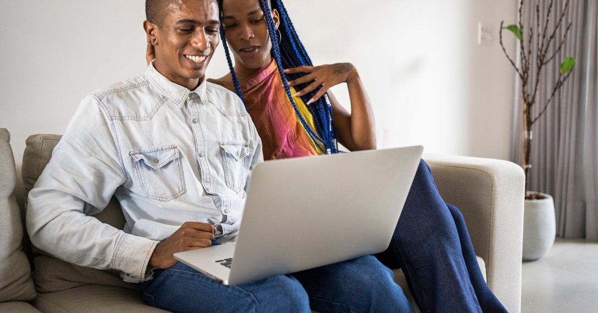 A couple uses a laptop on the couch at home.