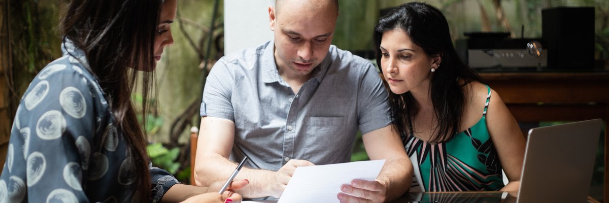 A couple reads financial paperwork with an advisor.