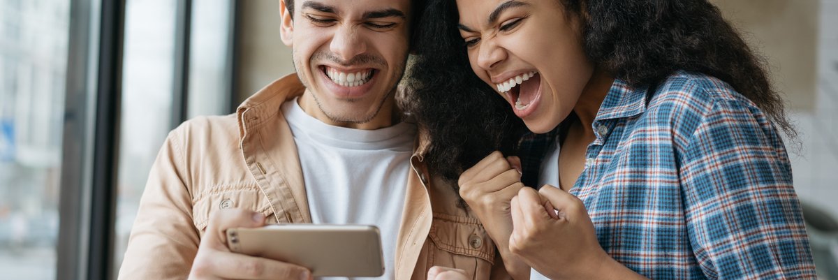 Two people excited over what's on cell phone.