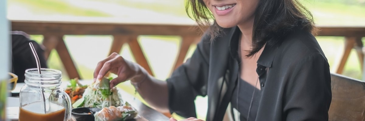 Someone happily uses a smart tablet while eating at a cafe outside.
