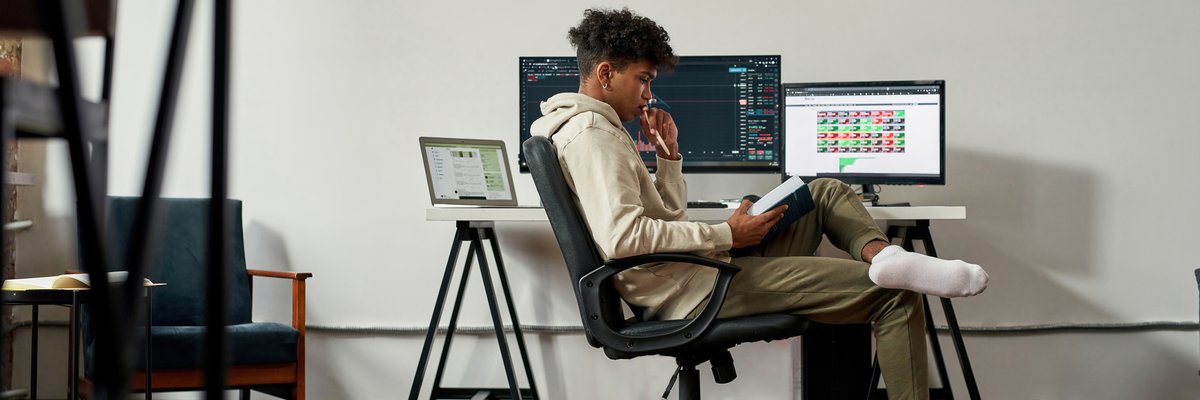 A young adult monitors the stock market while studying finance at home.