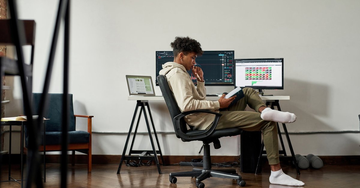 A young adult monitors the stock market while studying finance at home.