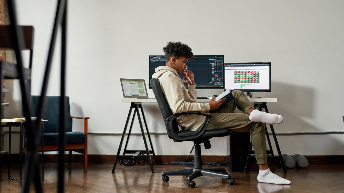 A young adult monitors the stock market while studying finance at home.