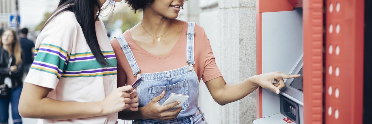 A couple withdraws money from an ATM machine.