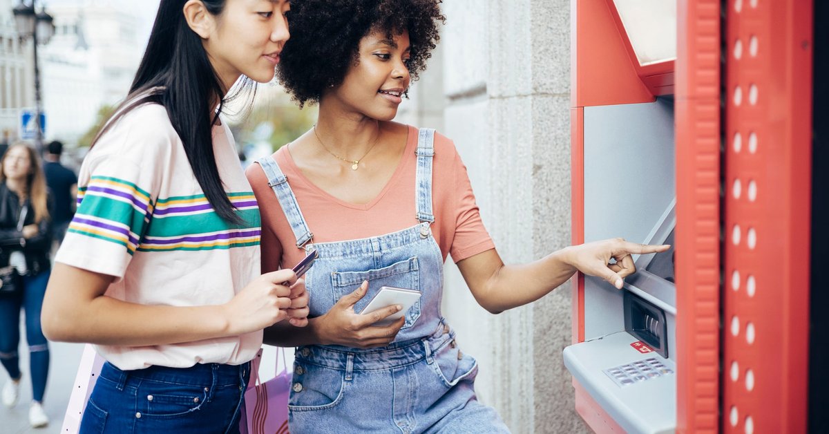A couple withdraws money from an ATM machine.