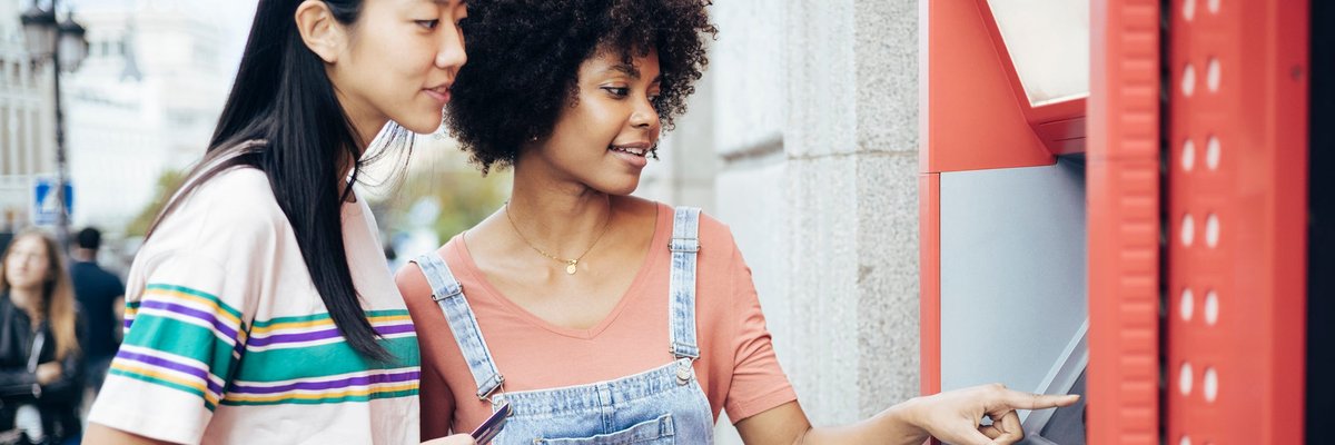 A couple withdraws money from an ATM machine.