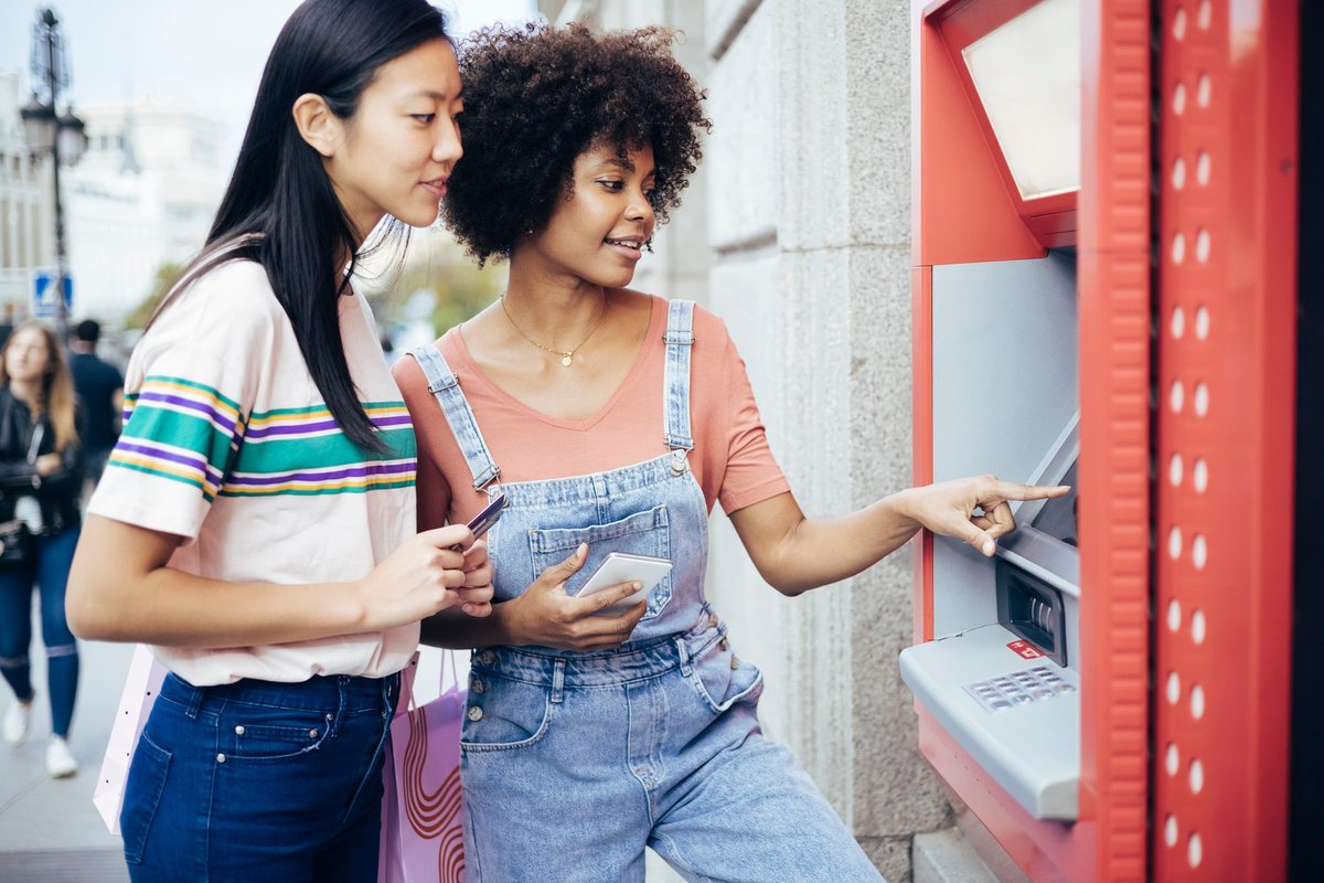 A couple withdraws money from an ATM machine.