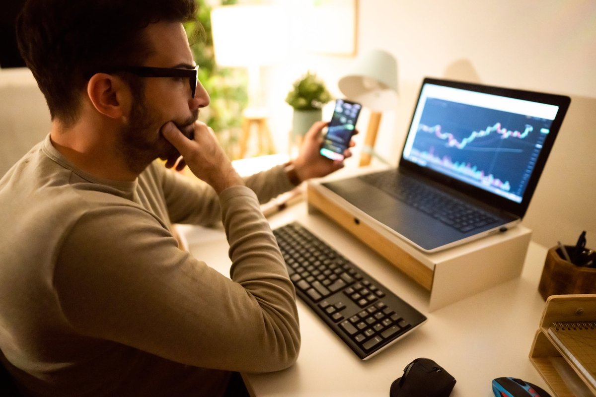 An adult analyzes a crypto chart on his laptop in his home office.