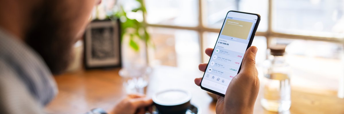 Person drinking coffee and holding cellphone with payment app open on screen.