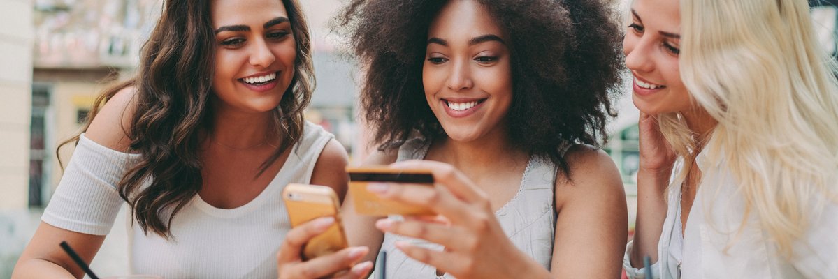 Three friends having drinks and looking at credit card.