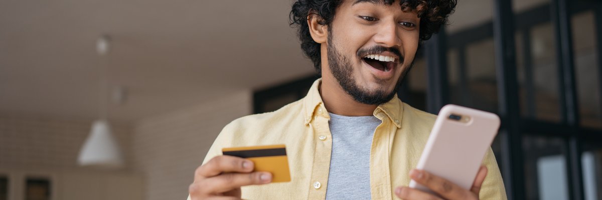 Excited man holding cell phone and credit card.