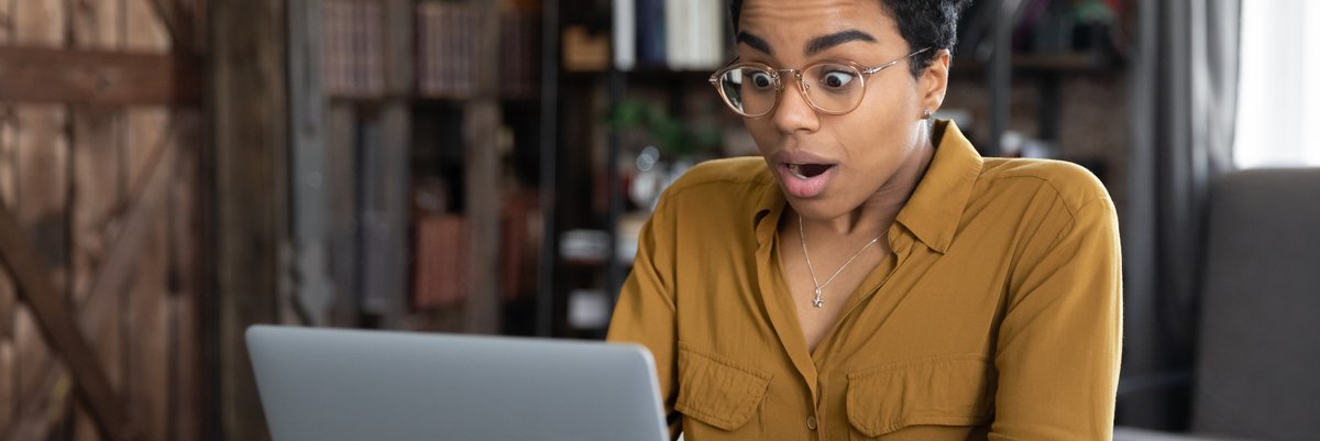 Person making a shocked expression while looking at laptop screen.