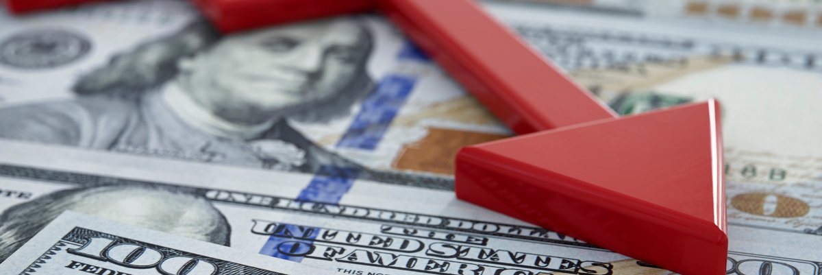 A downward trending red arrow over top hundred dollar bills.