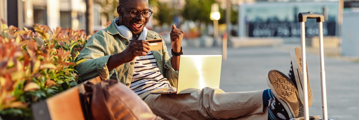 Man on bench with credit card and luggage.