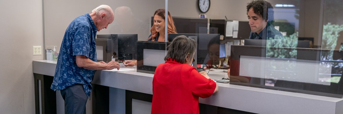Retirees getting assistance from bank tellers at bank.
