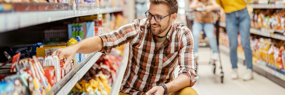 Man shopping in store aisle for groceries.