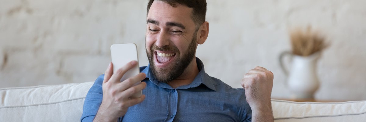 Happy man celebrating while looking at cellphone.