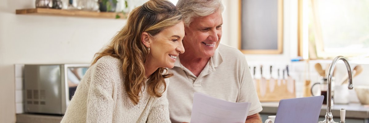 Mature couple looking at information on a laptop together.