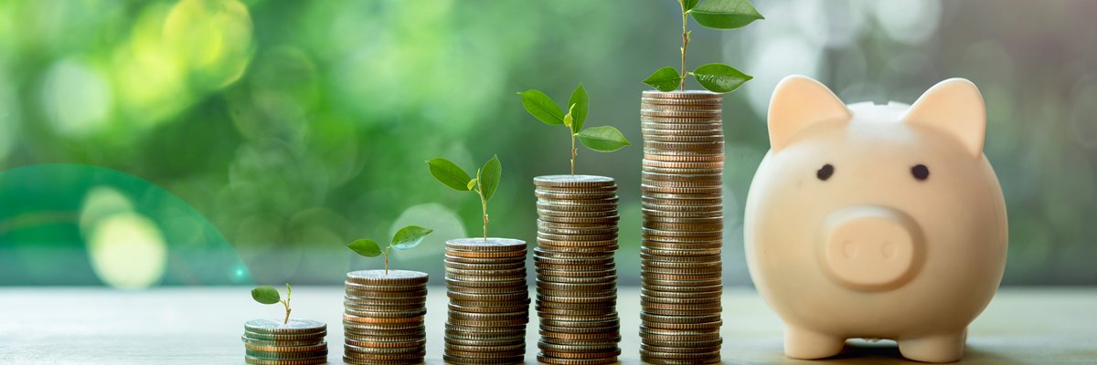 Stacks of coins sprouting leaves next to a small piggy bank.